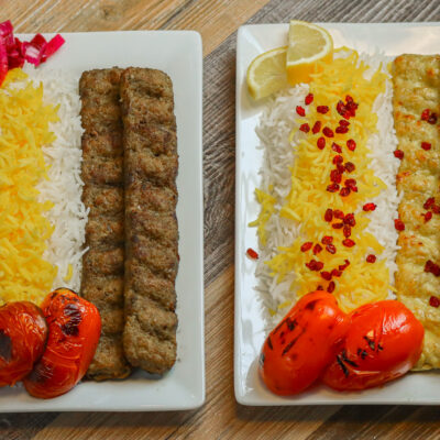 Ground beef and chicken kabob plates with saffron rice, grilled tomatoes, lemon, and pickled vegetables